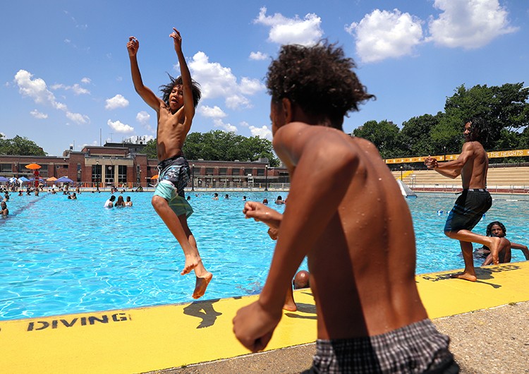 Kids jump into the water at the Highbridge Pool during a summer heatwave in Washington Heights in New York on Wednesday, July 20, 2022. Water bottles, with sweating beads of condensation, water guns, spraying in parks and inside apartments and fire hydrants transforming into sprinklers. These are some of the tools New Yorkers are using to work and play during the summer's first heat wave, as daily temperatures near 100 degrees. (Caitlin Ochs/The New York Times)