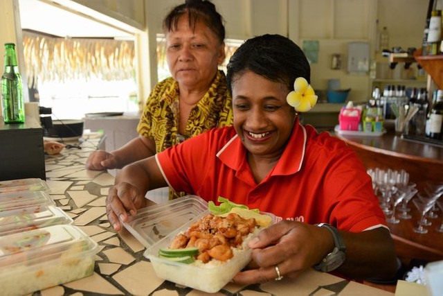 ダニエル・香奈さんがデリバリー販売する「BENTO」を興味津々に手にするホテルのスタッフら。この日のメニューは照り焼きチキンのような「ヤミーチキン丼」だった＝2022年6月23日、クック諸島ラロトンガ島、荒ちひろ撮影