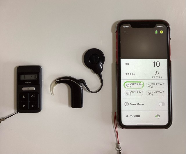 左から、人工内耳のリモコン、スピーチプロセッサ、送信コイル（丸い部分）、スマートフォンでできる操作用画面（画像提供：ぷーどるさん）