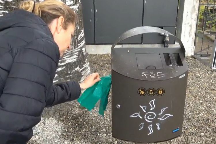犬のフン専用ゴミ箱から袋を取り出す住民