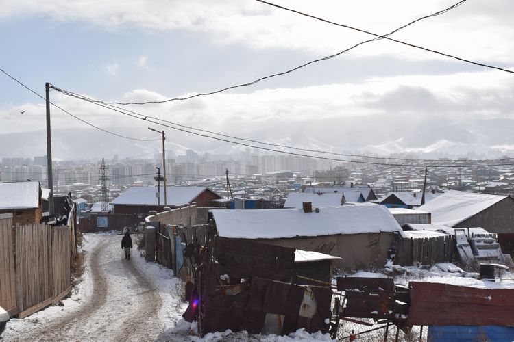 ウランバートルのゲル地区を歩く子ども。奥に高層マンションやビルが並ぶ中心部が見えた