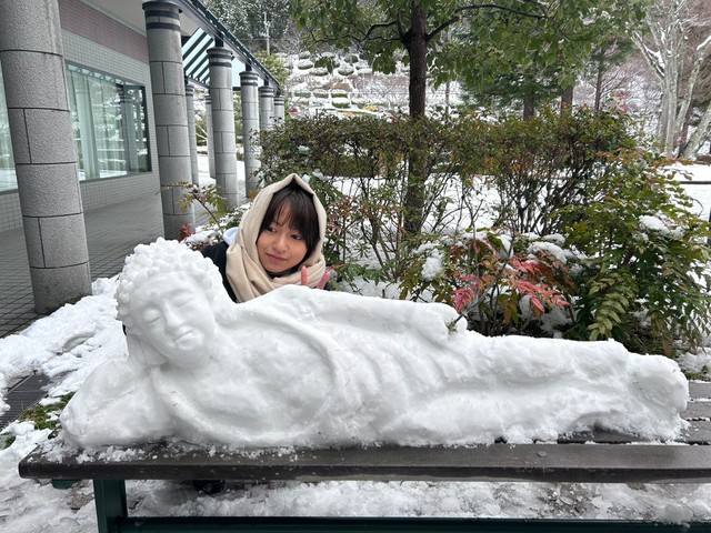 雪の仏像と写真におさまる濱里さん