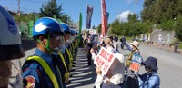 名護市辺野古への新基地建設に抗議してプラカードを掲げる人たちと警備員（提供画像）