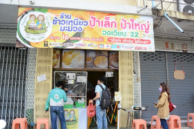 スムスィ・ナカサイさんのお店。午前中からお客さんが並んでいた。看板の左側にレックおばさん（右）とヤイおばさん（左）のイラストが描かれている＝４日、バンコク、翁長忠雄撮影撮影