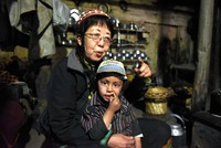 カラーシャの谷で親戚の男の子を抱えて座る和田晶子さん＝2019年4月17日、パキスタン北西部、乗京真知撮影