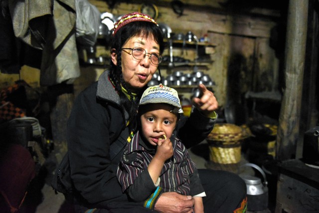 カラーシャの谷で親戚の男の子を抱えて座る和田晶子さん＝2019年4月17日、パキスタン北西部、乗京真知撮影