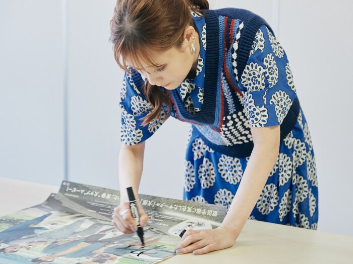 「犬部！」のポスターにサインをする大原さん。青森と東京を行ったり来たりのハードなロケのおかげで、ポスターにあるような、美しい自然の中でのシーンも盛りだくさんだ。