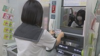 自ら考案した手作りのポップをATMに取り付ける高校生