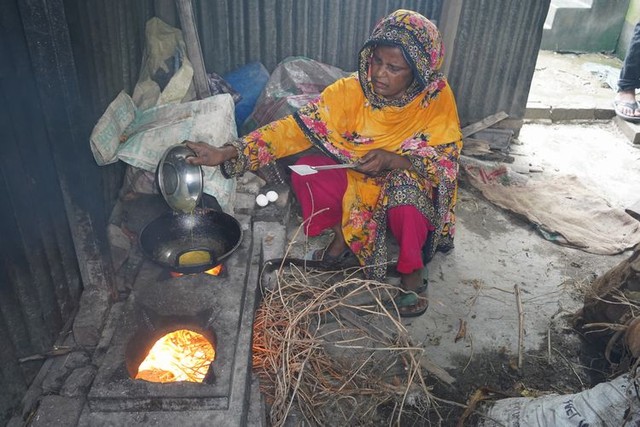 家の外にある台所で、枝を燃やして調理するモモタジュ・ベグンさん=2024年5月6日、ダッカ近郊、荒ちひろ撮影
