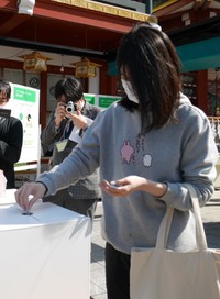 回収ボックスにアニメグッズを投入する台湾から旅行中という女性＝東京・神田神社