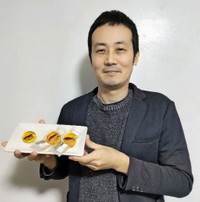 和菓子「太古の琥珀（こはく）糖」を手にする三島孝宜さん