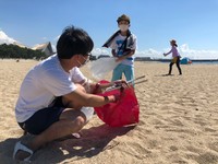 青く晴れた空の下、ごみを拾う参加者＝須磨海岸