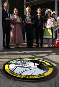 作者の宮島未奈さん（左から２人目）らが立ち合い、京阪膳所駅の近くに設置された主人公成瀬あかりを描いたマンホールのふた＝１９日、大津市馬場２丁目
