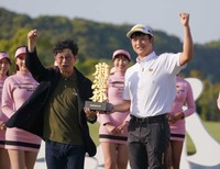 大会主催者の前沢友作氏（左）から優勝トロフィーを受け取りガッツポーズを決める小西たかのり