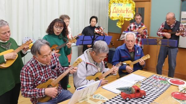 小林康夫さん夫婦（左端の２人）らウクレレサークルの仲間と演奏するアンディさん（奥右端）。和子さんは趣味のバイオリンで加わった