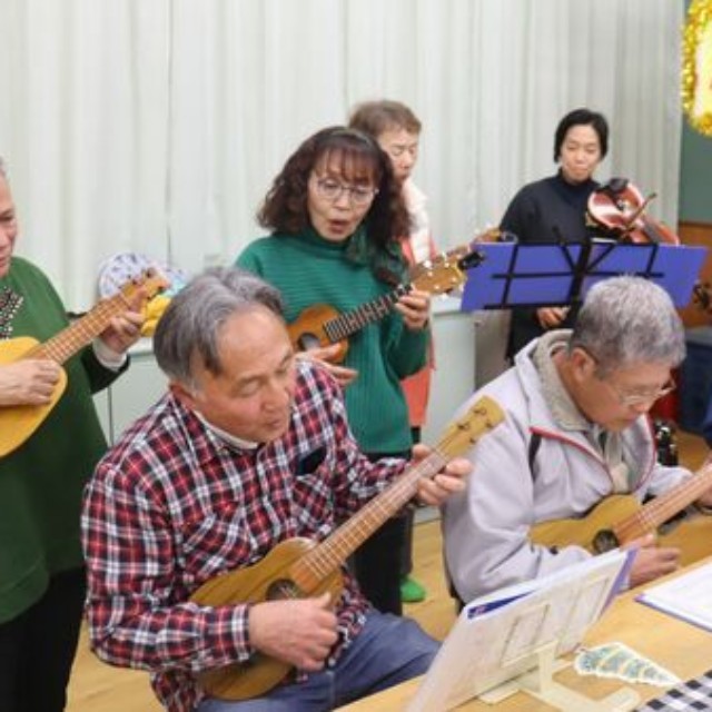 小林康夫さん夫婦（左端の２人）らウクレレサークルの仲間と演奏するアンディさん（奥右端）。和子さんは趣味のバイオリンで加わった