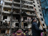 ロシアのロケット弾による攻撃で破壊されたマンション。住民らが片付けをしている