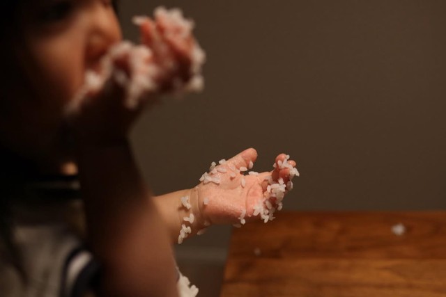 ごはんまみれの手を真剣に食べている子供／かなみさん（@kanami_nakahara）提供