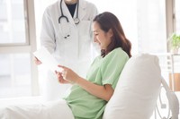 病院のベッドで書面を見る女性※画像はイメージです（Monet/stock.adobe.com）」
