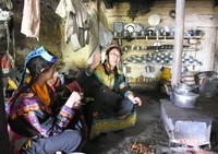 親戚の家で談笑する和田晶子さん（中央）。土間の中央に薪ストーブがあり、その上に鍋を置いて調理する＝2019年4月17日、パキスタン北西部、乗京真知撮影