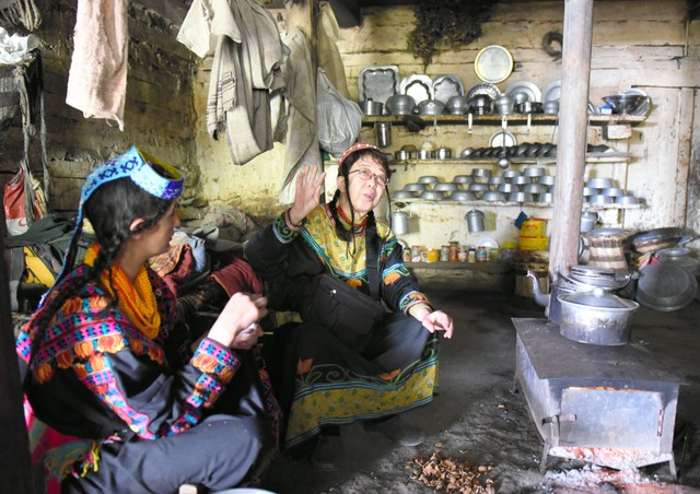 親戚の家で談笑する和田晶子さん（中央）。土間の中央に薪ストーブがあり、その上に鍋を置いて調理する＝2019年4月17日、パキスタン北西部、乗京真知撮影