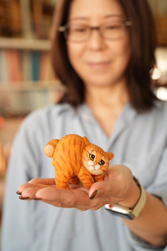 「やんのかステップ木彫り猫（ノーマルやんのか）」を手に持つHITOMIKOさん