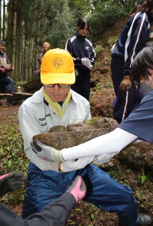 埋もれていた石仏を運び出す参加者たち（綾部市睦寄町）