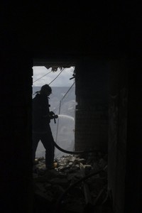 爆撃された建物を消火する消防士