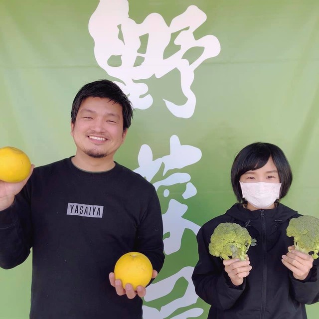 高知市内にある野菜専門店「野菜屋」の前で、堤健治さんとスタッフさん