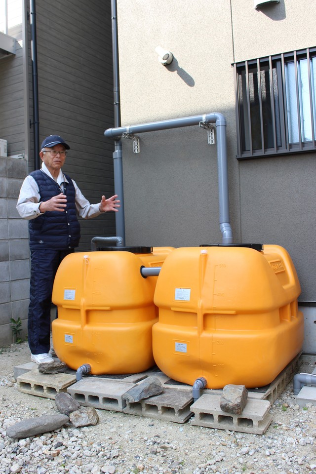 最大１トンの雨水をタンクにためられると説明する重本さん（向日市寺戸町）
