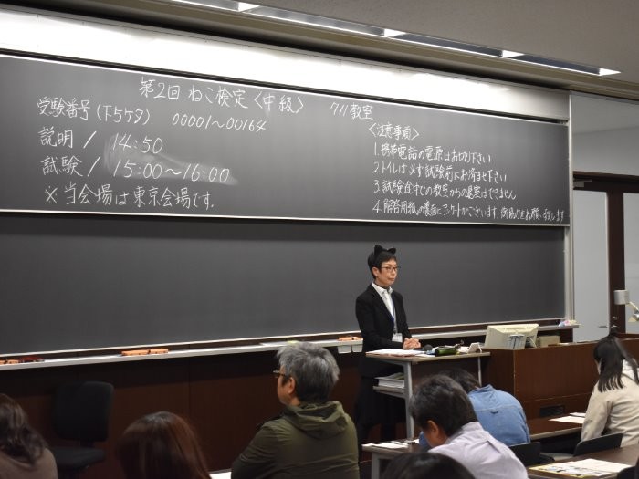 試験会場で猫耳をつけて説明する試験官　（提供＝日本出版販売）