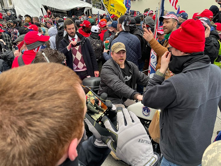 A photo provided by William Turton of Adam Newbold, a former member of the Navy SEALs, on a police motorcycle near the steps of the Capitol in Washington during the riot on Jan. 6, 2021. In the weeks since Adam Newbold, a former member of the Navy SEALs, was identified as part of the enraged crowd that descended on the Capitol on Jan. 6, he has been interviewed by the FBI and has resigned under pressure from jobs as a mentor and as a volunteer wrestling coach. (William Turton via The New York Times)  -- NO SALES; FOR EDITORIAL USE ONLY WITH NYT STORY CAPITOL-RIOT-SEAL BY DAVE PHILIPPS FOR JAN. 26, 2021. ALL OTHER USE PROHIBITED. --