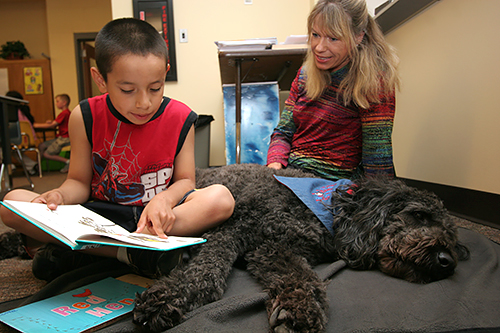 読み聞かせのあいだに犬がうとうとしても、子どもは気にせず、体にもたれて読み続ける