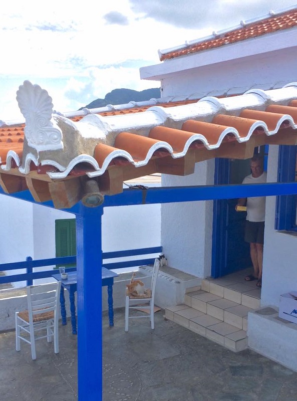 島の頂上にあるレストラン、昨日でシーズンオフを迎えて片付けが終わったところ。「この子たちもちょっと暇になるんだ」とオーナーが猫たちに餌を運ぶ（スコペロス島）