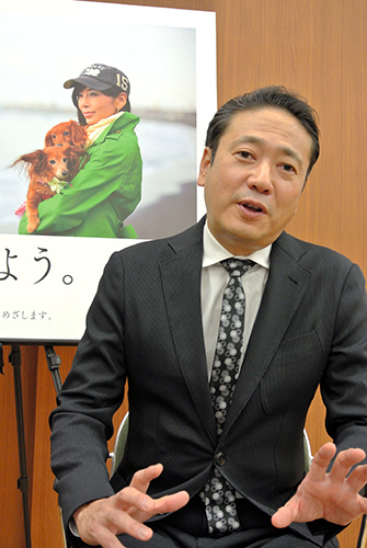 川島なお美さんがボランティアで協力した普及啓発ポスターの前で基金設立への思いを話す鎧塚俊彦さん