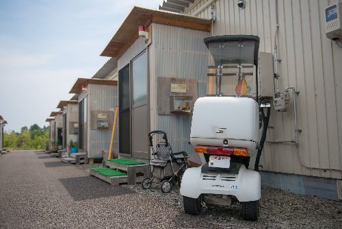 飼い主の男性の避難先仮設住宅と、一時帰宅に使ったバイク写真＝上村雄高