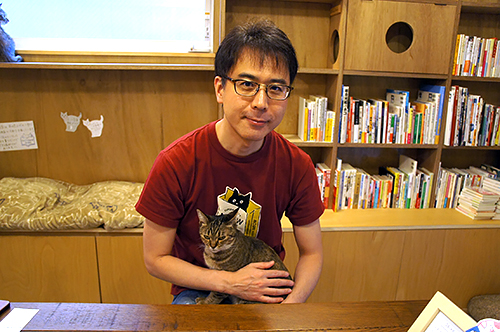 「Cat’s Meow Books（キャッツミャウブックス）」店主の安村正也さんと抱っこされる「鈴」ちゃん