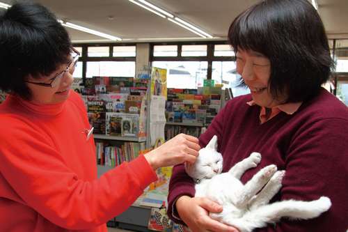 しろを宝もののように優しく抱く常連客の坂本さん（右）と、書店のスタッフで猫写真担当の須藤さん
